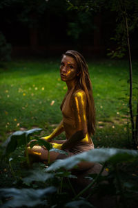 Young woman with golden skin sitting in the garden