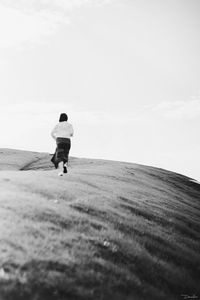 Rear view of boy on umbrella against sky