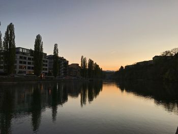 Reflection of buildings in lake against clear sky