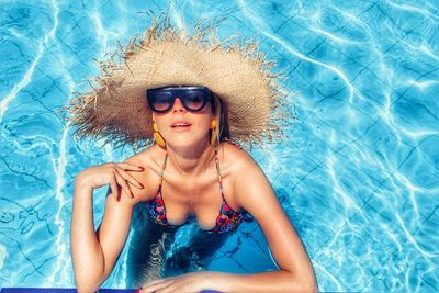 Young woman wearing sunglasses in swimming pool