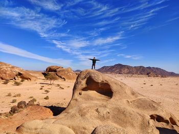 Man standing on rock against sky