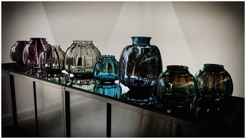 Close-up of glass bottles on table against wall