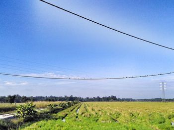 Electricity pylon on field against cloudy sky