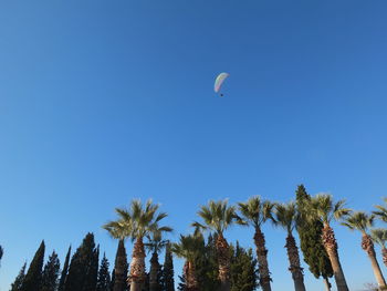 Low angle view of person paragliding against clear blue sky