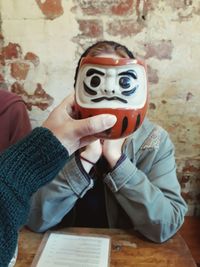 Midsection of person holding mask on table