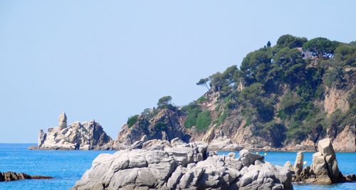 Scenic view of rocky cliff and sea against clear sky