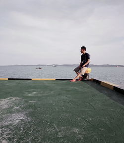 Young man on sea against sky