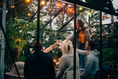 Happy male and female friends toasting wineglasses in glass cabin