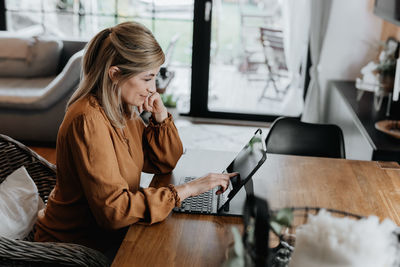 Side view of businesswoman talking on phone at home