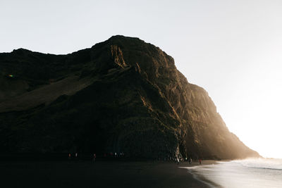 People on beach against mountain