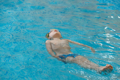 Boy floating on the back in the water in indoor swimming pool. relaxing and balancing. physical