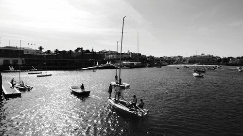 Boats moored at harbor against sky in city