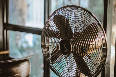 Close-up of vintage electric fan by window at home