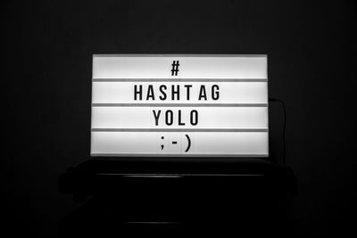 Close-up of placard with hashtag and yolo text over black background