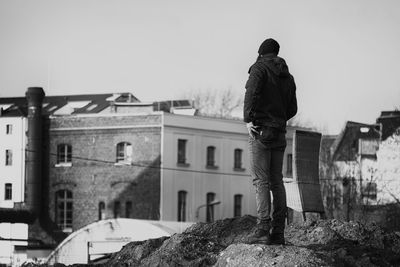 Rear view of man looking at buildings against clear sky