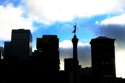 Low angle view of modern buildings against cloudy sky