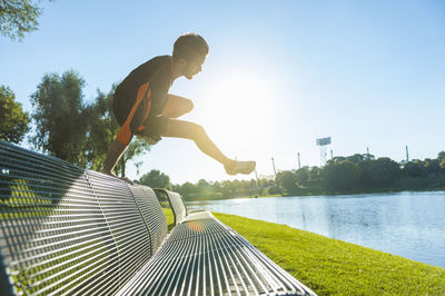 Athlete jumping over bench at the riverside