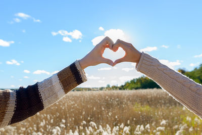 Midsection of man holding heart shape against sky