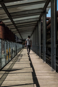 Rear view of man walking on bridge