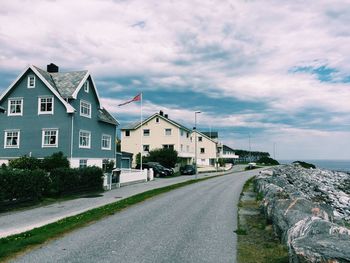 Houses by street amidst buildings against sky