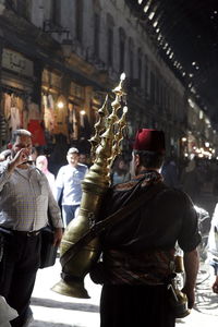 Rear view of man carrying decor equipment on street at night