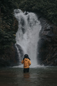 Mature man standing against waterfall
