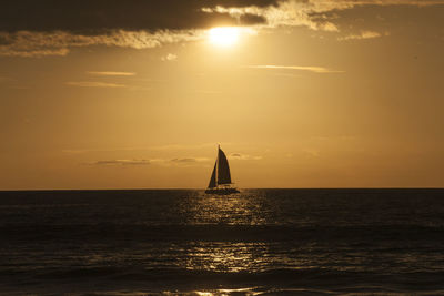 Silhouette sailboat sailing on sea against sky during sunset