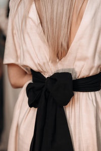 Beige elegant feminine fashion details spring summer dress with big black bow at the back. backstage