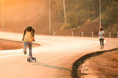 Rear view of girl riding push scooter on road