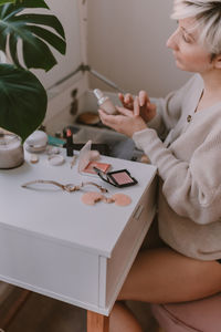 Woman holding paper while sitting on table at home