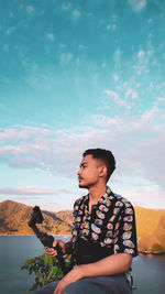 Man holding camera against sky