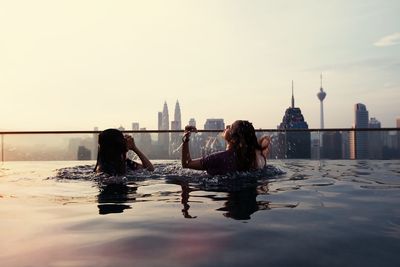 Women swimming in infinity pool during sunset