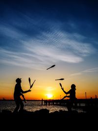 Silhouette men fishing at sunset
