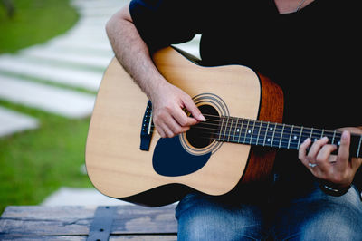 Midsection of man playing guitar