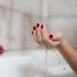 Midsection of woman holding water drops on glass