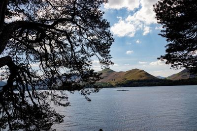 Scenic view of lake by tree mountain against sky