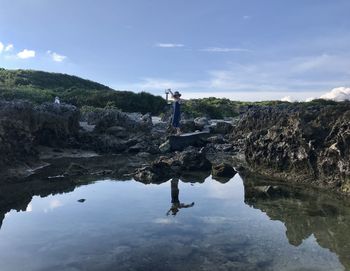 Man standing on rock against sky