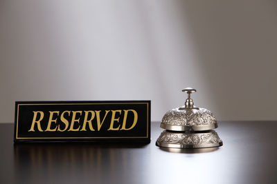 Close-up of reserved place card with service bell on table