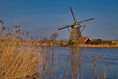 Traditional windmill on lake against sky