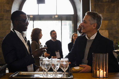 Business delegates discussing while holding glasses at seminar