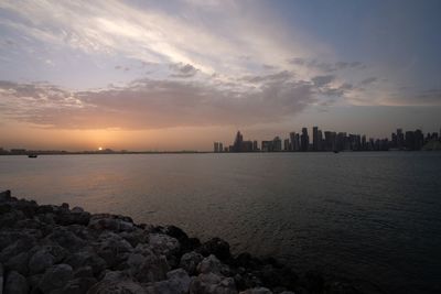 Scenic view of sea and buildings against sky during sunset