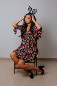 Young woman sitting against wall