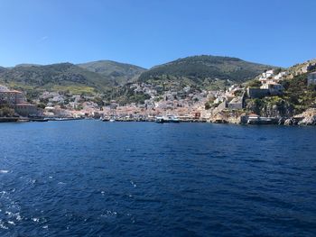 Town by sea against clear blue sky