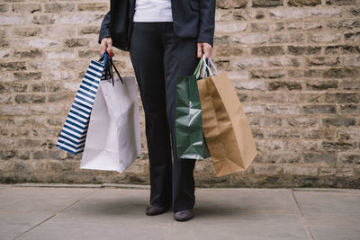 Woman standing with shopping bags at footpath