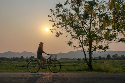 Woman riding bicycle on road against sky