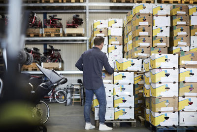 Rear view of mature male volunteer arranging boxes at warehouse