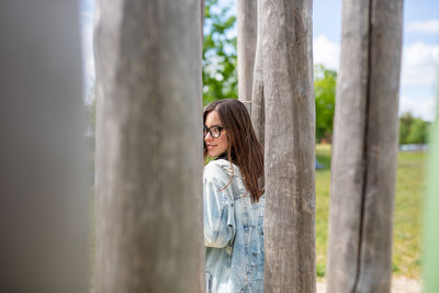 Side view of woman standing by tree trunk