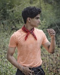 Young man looking away while standing on field