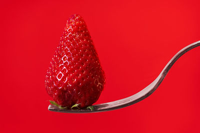 Close-up of strawberry over red background