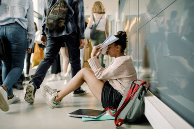 Teenage girl with book concentrating while sitting in school corridor